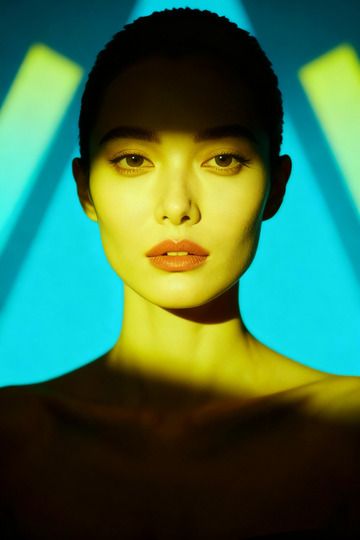 Femme de face, lumière jaune, faisceaux cyan en fond