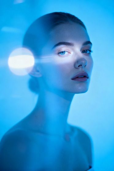 Femme de trois quarts, fond bleu clair, halo de lumière